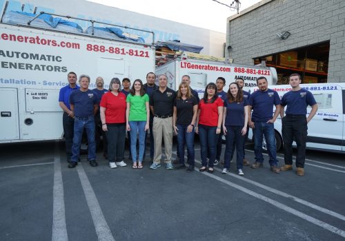The LT Generators team standing in front of two LT service trucks.