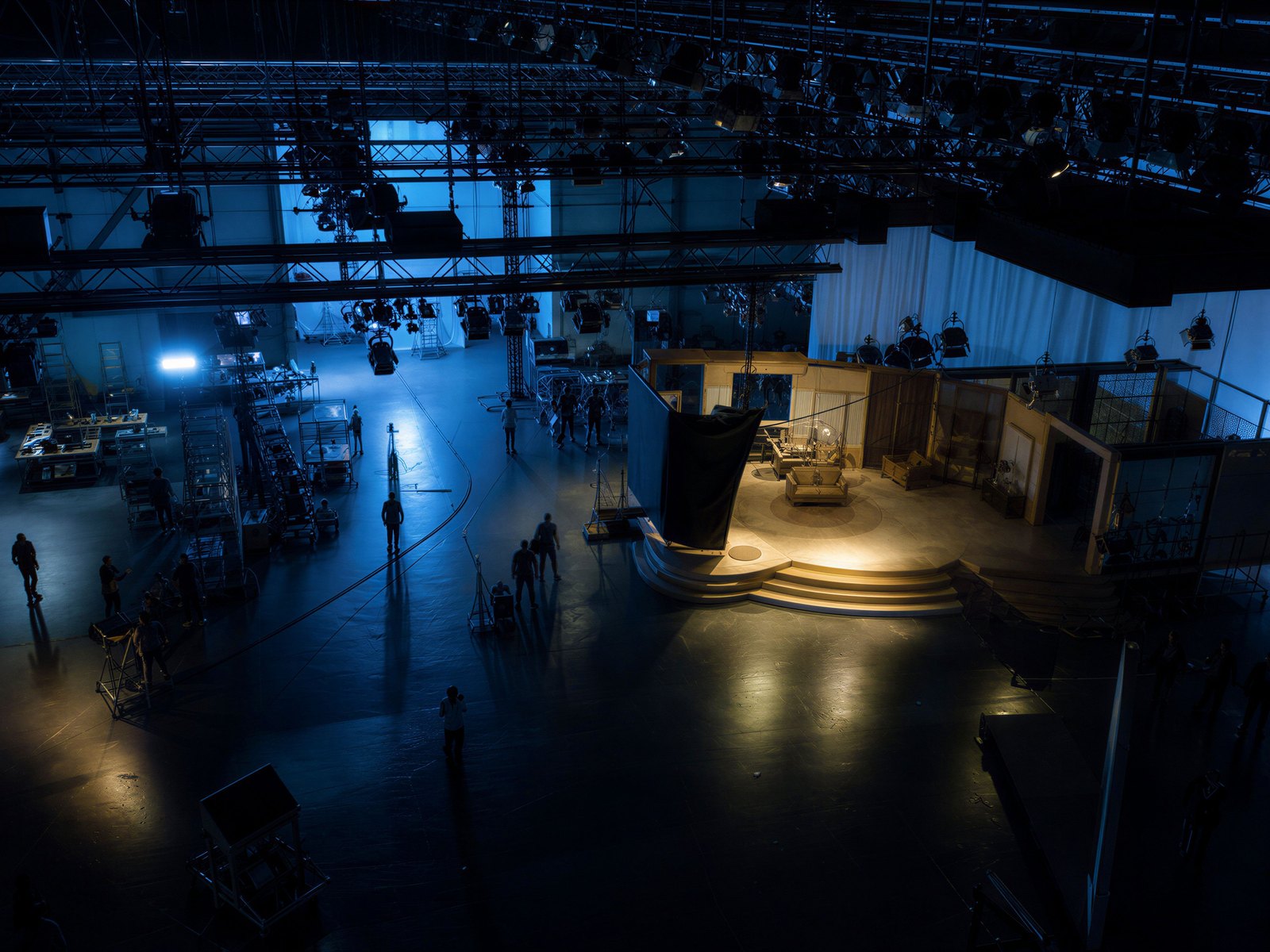 A television studio floor seen from the gantry: rigging, lights, and a half-built set